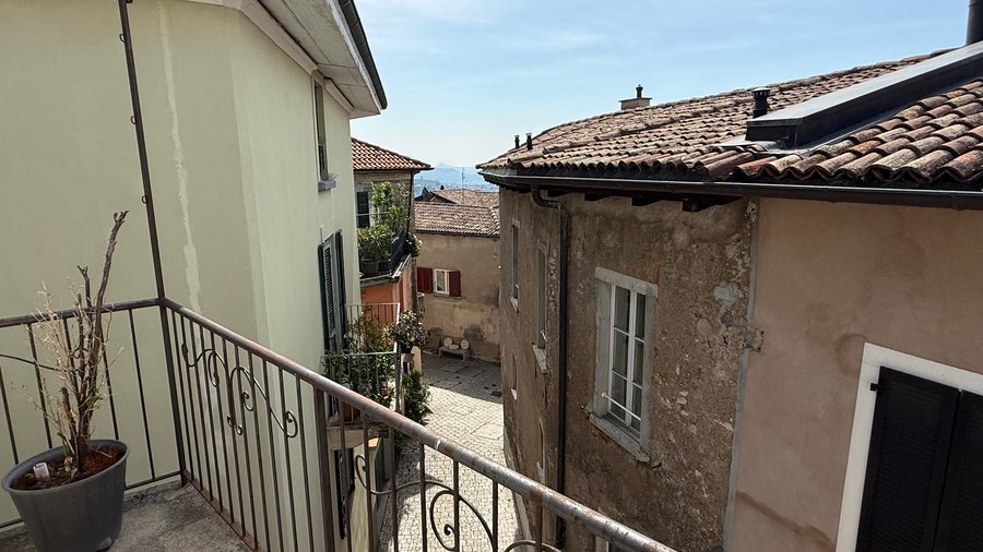 Balcone con ringhiera in ferro e vista sui tetti in pietra del nucleo
