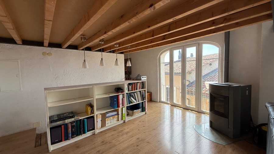 Spazio sotto il soppalco con travi, libreria, stufa a pellet e portefinestre ad arco